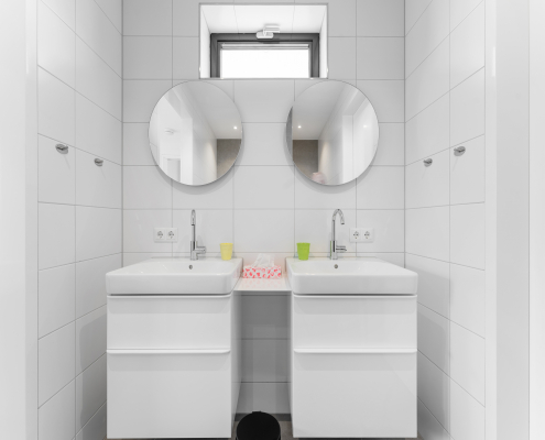 Badezimmer mit 2 waschbecken und 2 Spiegeln, weiße fliesen, kleines fenster über den spiegeln